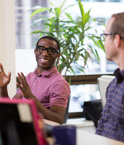 Two employees chatting at their desks
