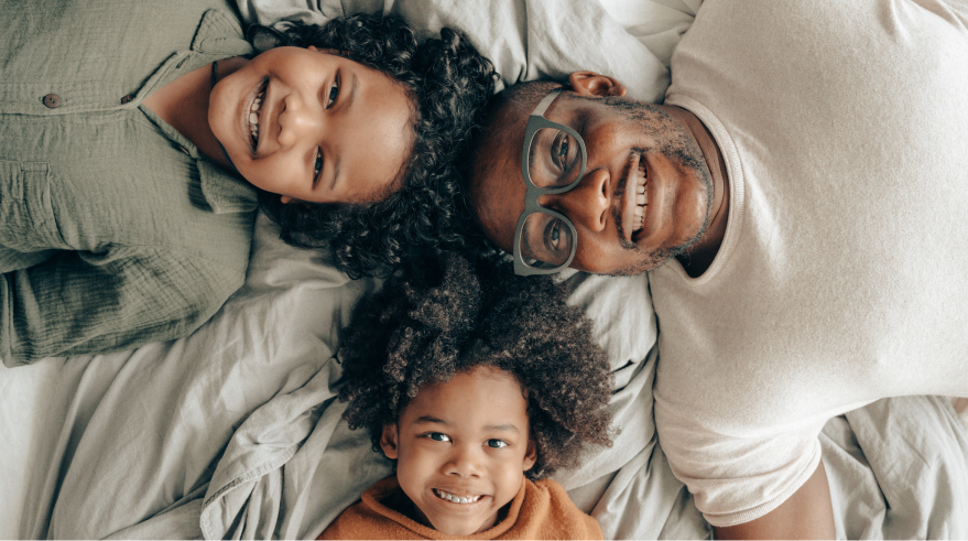 A family lying on a bed smiling