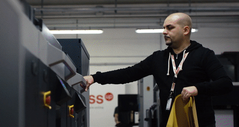 A person opening a large printer to add paper
