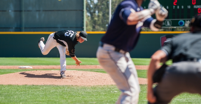 A baseball player throws a pitch to a batter
