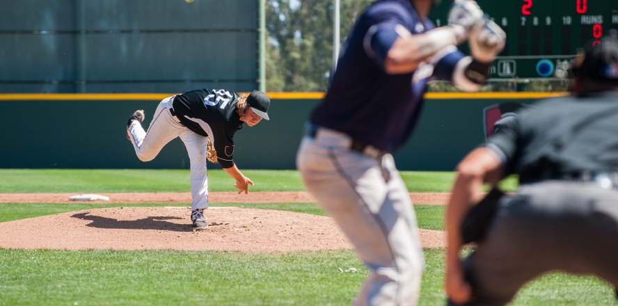 A baseball player throws a pitch to a batter